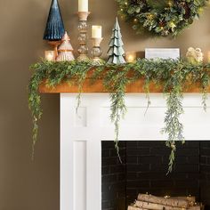 a mantel decorated with greenery, candles and christmas wreaths on top of it