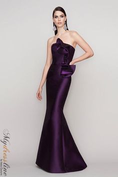 a woman in a long purple dress posing for the camera with her hands on her hips