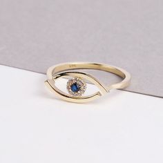 The 14K Evil Eye Ring is a stunning and intricate piece of jewelry that is perfect for any occasion. The ring features a beautiful Evil Eye design, with sparkling CZ diamonds and a vibrant blue sapphire. The Evil Eye is depicted on the ring, adding to its symbolism of protection and good luck. This ring is perfect for everyday wear or as a special occasion piece, and would make a thoughtful gift for any woman in your life. Whether you're looking for a gift for Christmas, Father's Day, Mother's D Elegant Formal Rings With Diamond Eyes, Gold Sapphire Stackable Rings For Gift, Elegant Rings With Diamond Eyes For Anniversary, 14k Gold Ring With Diamond Eyes, Elegant Ring With Diamond Eyes For Anniversary, Exquisite Round Sapphire Ring Gift, Exquisite Round Sapphire Ring As Gift, Gold Cubic Zirconia Ring With Halo Detail, Exquisite Cubic Zirconia Ring For Gift