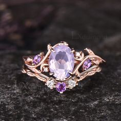 a ring with an amethorate and purple stones on the side, sitting on top of a rock