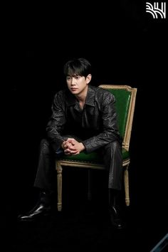 a man sitting on top of a green chair in front of a black background,