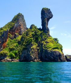 an island in the middle of water with rocks sticking out of it's sides