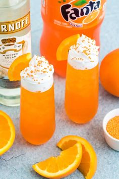 an orange drink with whipped cream and garnish on the rim next to sliced oranges