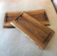 two wooden serving trays sitting on top of a couch next to eachother