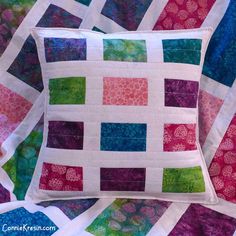 a colorful quilted pillow sitting on top of a bed