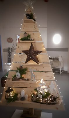 a christmas tree made out of wooden planks with lights around it and decorations on the top