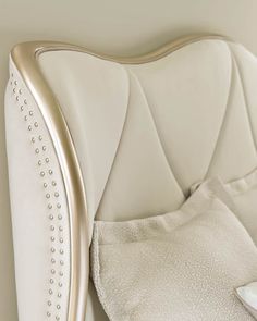 a close up of a bed with a white headboard and pillows on top of it