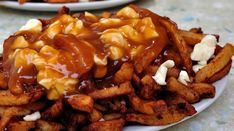 a white plate topped with french fries covered in caramel sauce and cheesy topping