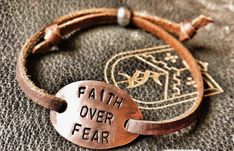 a leather bracelet with a metal tag that says faith over fear