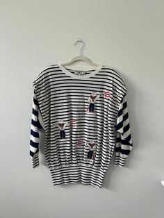 Super unique top or tunic with a combination of stripes and nautical sailor embroidered figures. Grommets along the shoulders. Tag says 1X but fits smaller. This could be great on with linen pants or as a beach sweater. Cotton Nautical Tops For Vacation, White Nautical Tops For Vacation, Nautical Cotton Tops For Vacation, White Vertical Stripes Top For Vacation, Nautical Style Cotton Tops For Vacation, Striped Crew Neck Tops For Vacation, Marine Style Cotton Tops For Summer, Summer Marine Style Cotton Tops, Nautical Cotton Tops For The Beach