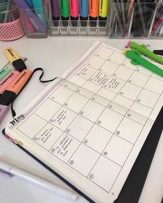 two notebooks with markers, pens and pencils next to each other on a desk