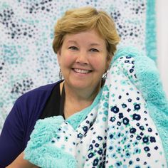 a woman is smiling while holding a blue and white blanket