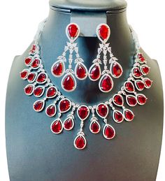 Enhance your jewelry collection with our CZ American Diamond and Red Stone Necklace set. This elegant set is perfect for any party or special occasion. The combination of CZ diamonds and red stones adds a touch of sophistication and glamour. Up your style game and stand out from the crowd with this stunning necklace set. Jewellery Care- Keep the jewellery dry, avoid contact with perfumes and water. Cheap Red Jewelry For Diwali, Dazzling Ruby Necklace For Party, Luxury Red Hand Set Necklaces, Luxury Hand Set Red Necklaces, Luxury Red Hand-set Necklaces, Hand Set Ruby Bridal Necklace For Party, Dazzling Ruby Bridal Necklace For Parties, Formal Red Crystal Necklace, Ruby Necklaces With Sparkling Stones For Party