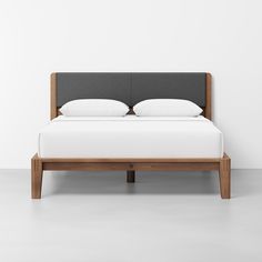 a bed with two pillows on top of it and a headboard made out of wood