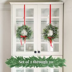 two wreaths on top of a white china cabinet with red ribbon around it and the words set of 2 through 20