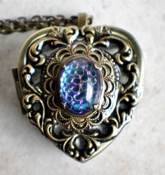 "Heart music box pendant. This heart shaped music box is inspired by the gorgeous music box pendants of era's gone by. Music box is pill box size, please look at the dimensions for exact size. A heart shaped locket has been adorned with a bronze stamping of a lacey edged floral heart with a elegant bronze filigree setting holding a gorgeous German helio scale back mosaic glass cabochon. The cabochon changes four different color as it is moved and the light hits it. The lacey edged floral heart a Vintage Brass Heart Pendant Jewelry, Vintage Bronze Heart Necklace, Collectible Medallion Jewelry For Valentine's Day, Heart-shaped Bronze Jewelry For Gifts, Vintage Heart Charm Jewelry Gift, Bronze Heart-shaped Jewelry For Gifts, Bronze Heart Pendant Jewelry With Heart Charm, Handmade Heart Pendant Jewelry Keepsake, Handmade Heart Pendant Jewelry For Keepsake