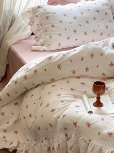 a white bed with pink and red flowers on the comforter, pillows and pillow cases