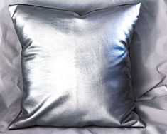 a silver pillow sitting on top of a bed