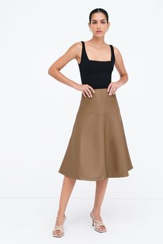 Our Lexi Skirt brings new life to the timeless A-line cut with architectural seam detailing that creates a striking silhouette. Fashioned from stretchy vegan leather with an invisible side zip, she offers an easy fit that accentuates your waist. Whether she's dressed up or down, Lexi arrives to every occasion with equal elegance. | Astrid, in latte and in black, is 5'9" (175 cm) tall, wearing size XS. Shannon, in black, is 5'8 (173 cm) tall, wearing size M. Total length is approximately 29.5" (7 Modern A-line Lined Skirt, Chic Brown A-line Bottoms, Modern A-line Relaxed Skirt, Chic Brown A-line Skirt, Modern A-line Skirt, Modern Full Skirt Fitted, Modern Fitted Full Skirt, Modern A-line Skirt For Work, Vegan Leather Skirt