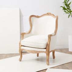 a white chair sitting on top of a wooden floor next to a potted plant