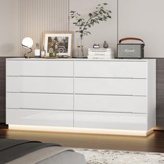 a white dresser sitting on top of a wooden floor next to a wall mounted clock