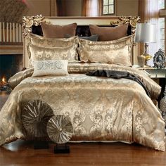 a bed with gold comforter and pillows in a room next to a fire place