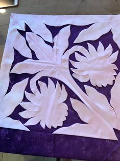 a purple and white piece of paper with leaves on it, sitting on a table