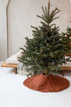 a small christmas tree sitting on top of a white floor next to a bed in a room