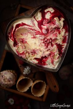 a heart shaped dish filled with red and white ice cream next to other desserts