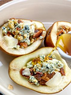 two baked potatoes on a plate with butter and other toppings