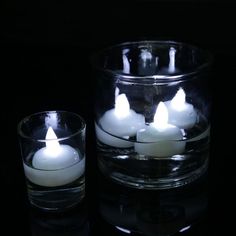 some white candles are in a glass bowl