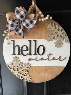 a wooden sign that says hello winter with snowflakes hanging from the front door