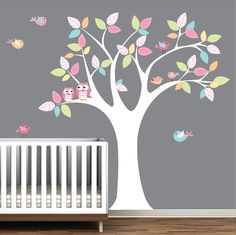 a baby's nursery room with a tree and owls on the branch wall decal