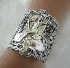 "This beautiful bracelet has a silver plated filigree cuff, silver plated chain, silver plated goddess and silver plated leaf accents. 3\" wide. Silver plated lobster clasp. 7\" long adjustable to 9\" long." Silver Spiritual Metal Cuff Bracelet, Spiritual Silver Metal Cuff Bracelet, Silver Gothic Bracelets For Festival, Handmade Spiritual Silver Cuff Bracelet, Handmade Silver Spiritual Cuff Bracelet, Gothic Silver Bracelet, Silver Gothic Bangle, Spiritual Silver Cuff Bracelet With Intricate Design, Silver Bohemian Cuff Bracelet Gift