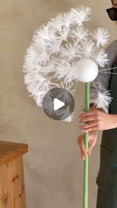 a person holding a fake dandelion in their hand