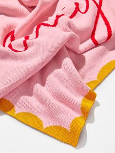 a pink sweater with yellow and red designs on the front, sitting on top of a white surface