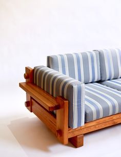 a striped couch sitting on top of a white floor next to a wooden frame and foot rest