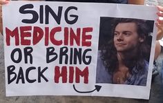 a man holding up a sign that says sing medicine or bring back him