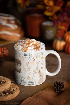 a cup of hot chocolate with marshmallows on the side and cookies next to it