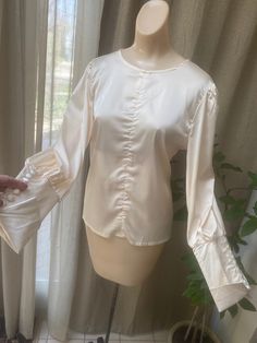 "Wonderful never worn silky feel/look blouse with the manufacturer tag still attached. Size tag says Medium but I think it would be better for a lady who wears a Small blouse from the way it fits my size Small dress form. The fabric tag in a side seam says this is 65% cotton and 35% polyester which I find strange as the fabric feels just like silk. I don't see any indication of cotton. Nevertheless the blouse is special, and anyone who sees you wearing it will assume it is fine pure silk. Can be Formal Long Sleeve Blouse With Gathered Sleeves, Cream Blouse With Blouson Bishop Sleeves, Feminine Long Sleeve Satin Tops, Cream Blouse With Puff Blouson Sleeves, Elegant Beige Tops With Blouson Sleeves, Cream Blouse With Blouson Puff Sleeves, Elegant Beige Lantern Sleeve Top, Beige Long Sleeve Evening Blouse, Beige Long Sleeve Blouse For Evening