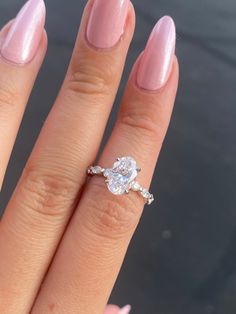 a close up of a person's hand with a ring on her finger and a pink manicure