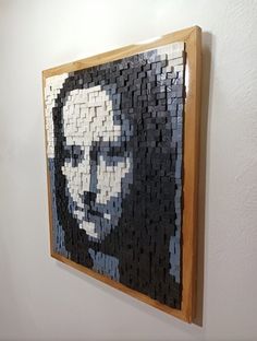 a large piece of art made out of legos is hanging on the wall next to a white wall