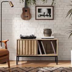 a living room with an entertainment center and guitar on the wall next to potted plants