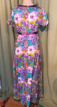 "This is a lovely vintage maxi dress or gown from the 70s. No brand label, appears to be home sewn. Bust is 34\", see measurements below. It is a pretty floral pattern in shades of pink, lavender, brown, turquoise, & green on a white background. Made of a satiny, nylon blend with a satin lining. It has a V neck, criss-cross ribbon trim on the bust & empire waist, plus short sleeves. Zips in the back with a nylon zipper. The dress is in very good vintage condition! No stains, spots or dis 1970s Vintage Maxi Dress, Vintage Maxi Length Dress, Purple Vintage Dress For Spring, Vintage A-line Maxi Dress For Garden Party, Vintage Pink Maxi Dress For Daywear, Retro Floral Print Maxi Dress For Daywear, Vintage Lavender Dress For Daywear, Vintage Purple Floral Print Dress, Retro Daywear Maxi Dress