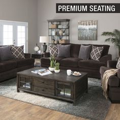 a living room filled with furniture and a coffee table on top of a rug in front of a window