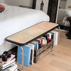 a bed sitting next to a stack of books on top of a wooden floor