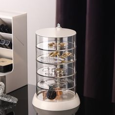 a jewelry organizer on a table next to a watch and other items in a box