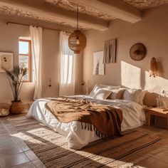 a bed sitting in a bedroom next to a window with sun streaming through it and a rug on the floor