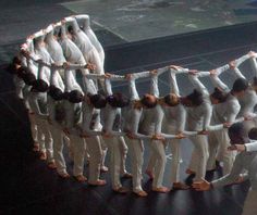 a group of people standing around each other in front of a mirror with their arms stretched out