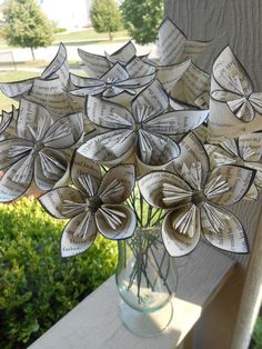 a vase filled with paper flowers sitting on top of a wooden table next to a window